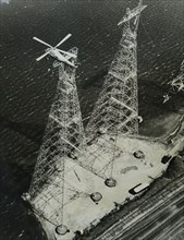Photograph of a helicopter being used to aid the construction of a utility power tower