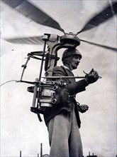 Photograph of Georges Sablier demonstrating his latest invention, a portable helicopter for which he won a special award at the international helicopter competition and show at Saint Etienne, Central ...