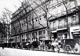 Photograph of horse drawn taxi cabs line a street in Paris, during the German occupation of France