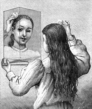 A young girl looking at herself in a mirror