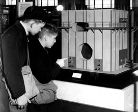 Photograph of two young school boys looking at a model of Britain's first atomic pile, now known as a nuclear reactor