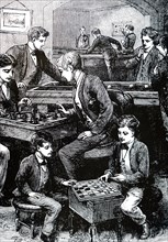 Boys in a games room amusing themselves with, among other things, chess and draughts