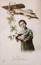French postcard with image of a boy holding flowers with an aircraft above
