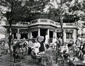 Photograph of people having tea sitting at tables and chairs outside the Ceylan Tea House.