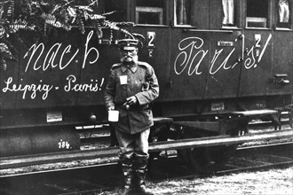 Germany, soldier in front of a train marked "To Paris!"
