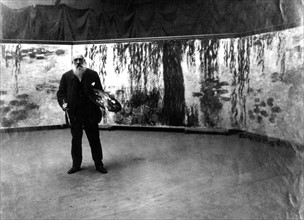 Painter Claude Monet in front of his 'Waterlilies' paintings