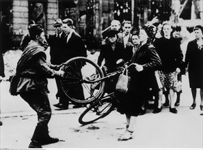 A Soviet soldier trying to take away a bicycle from a young woman, 1945