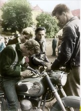 Young men gathered around a motor scooter, 1957