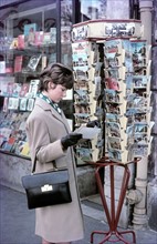 A woman looks at a postcard of Paris
-