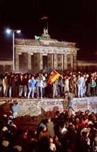 Deutschland, DDR, Berlin,  Ost-Berlin : Fall der Berliner Mauer 09.11.1989)  : Menschen sitzen auf der Mauer am Brandenburger Tor  am Abend des  10.11.1989
