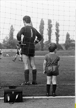 Fussballspiel der Amateurklasse, ein kleiner Junge steht direkt hinter dem Torhueter und schaut fasziniert dem Spiel zu, VfB Bottrop gegen RSV Klosterhardt (Oberhausen), Landesliga 1969/ 1970