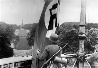 German soldiers run up the nazi flag in an occupied town of Luxemburg