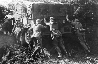 German soldiers pushing a vehicle stuck in the mud