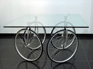 Glastisch auf Fahrradraedern von Designer Gae Aulenti
