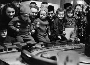Kinder betrachten Spielzeug in einem weihnachtlichen Schaufenster