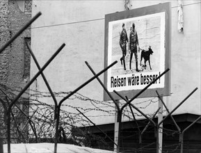 Germany / GDR, Berlin. Propaganda poster at the wall: "Travelling would be better!". It was set up by "Studio am Stacheldraht" - a West-Berlin radio station, broadcasting to East-Berlin. 1967