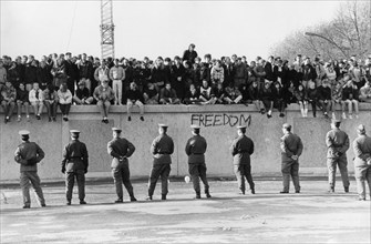 Germany / GDR Berlin: The fall of the wall. People on the wall. In front of them Vopos (border guards).