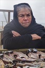 Older woman sells fish on the beach of Nazare