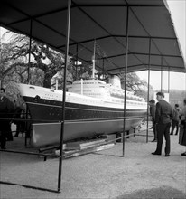 Visitors look at the model of a cruise ship exhibited around 1950