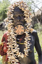 Old woman with lip plates and shells as headdress