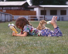 Girl feeds young lions and reads a book