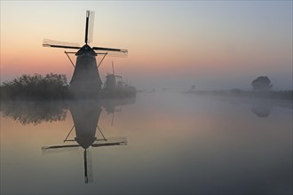 Historical windmills in the early morning fog at dawn