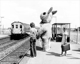 Big rabbit waits with passengers at the platform of a train station