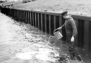 Man pours water from a watering can into the river