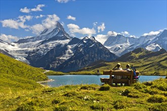 Hikers pausing on a wooden bench at lake Bachalpsee