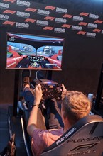 Visitors in driving simulator F1 2018 in front of screen with computer game