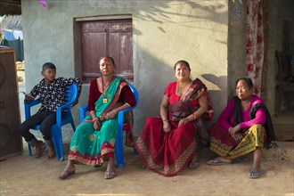 Nepalese women from the Tharu ethnic group sitting in front of a house during a wedding