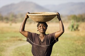 Tonga woman carries a basket with millet to her village at the Lake Kariba