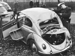 Police officer inspects VW beetle with total damage