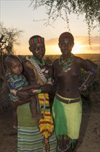 Two young women with infants from the Hamer tribe at sunset