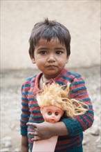 Small child with doll in the slum at the Ghazipur garbage dump