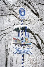 Beer garden sign in front of snow-covered trees