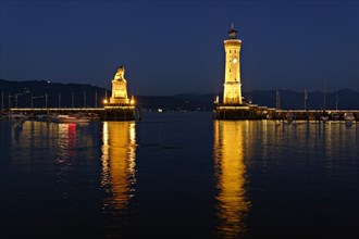 Illuminated Bavarian lion and the lighthouse at dusk