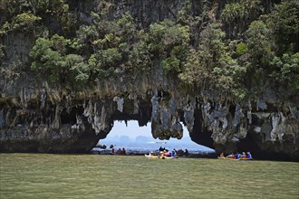 Tourists exploring eroded limestone rocks with canoes in Phang Nga Bay