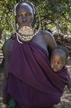 Woman with lip plate and headdress with baby