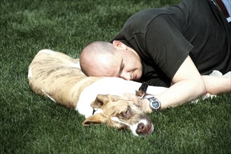 Man sleeps with dog as pillow