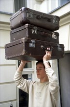 Young person carries three suitcases
