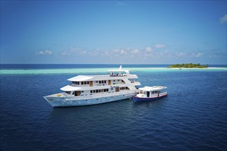 Diving safari ship MS Keana with diving dhoni anchored off an uninhabited palm island