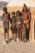 Himbafrau and children in front of a mud hut