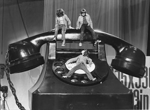 Three children on a large telephone