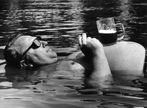 Man drinks beer in the water ca. 1970s
