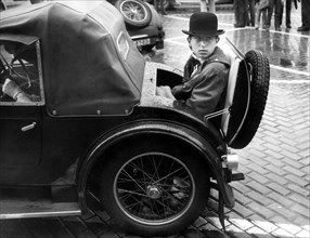 Boy sits in the boot of a vintage car from the 1970s