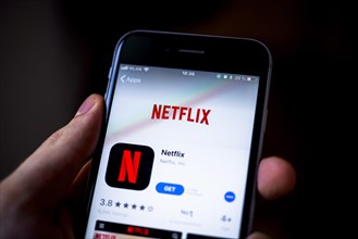 Hand holding iPhone with Netflix App in the Apple App Store