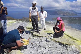 Volcanologists check sulfur fumaroles and chloride crusts on the crater rim