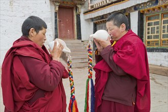 Buddhist nuns in the Terdom monastery call with the conch horn