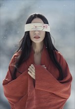Beautiful asian woman with a long black hair and a blindfold over her eyes